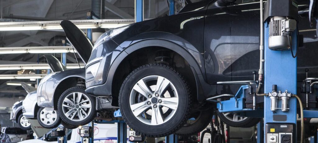 Mechanic inspecting a used car on a lift before export from Japan