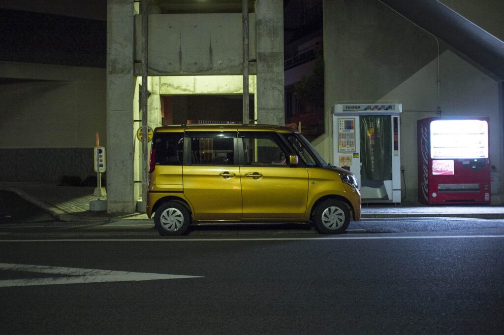 Yellow kei car parked at night in Japan